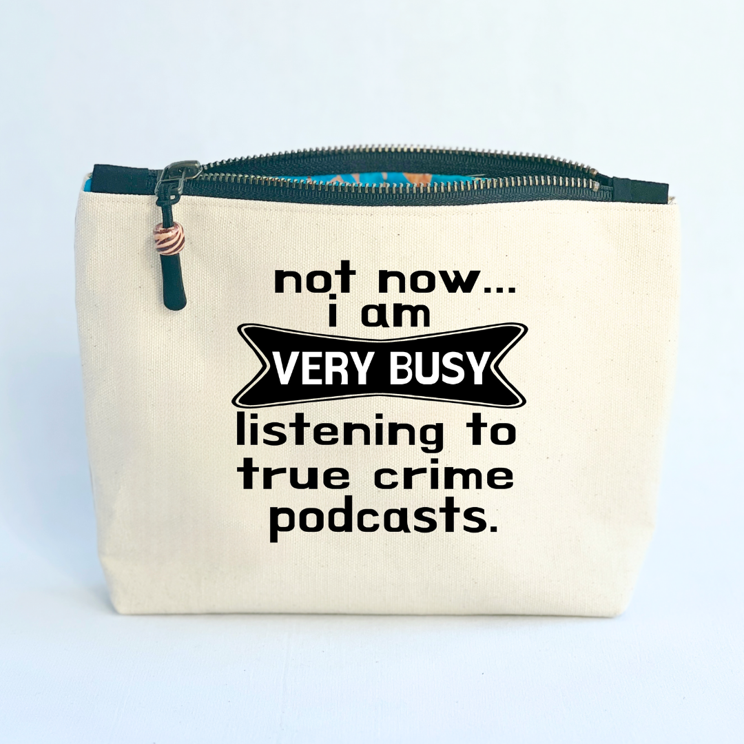square linen-color canvas zip bag with black zipper and the words, not now..I am very busy listening to true crime podcasts.