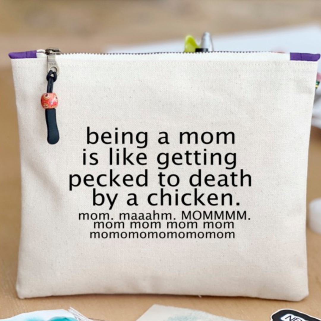 canvas zip bag measuring 9x7 with the words, "being a mom is like getting pecked to death by a chicken. mom. maahm. MOMMMMM!" in black lettering.