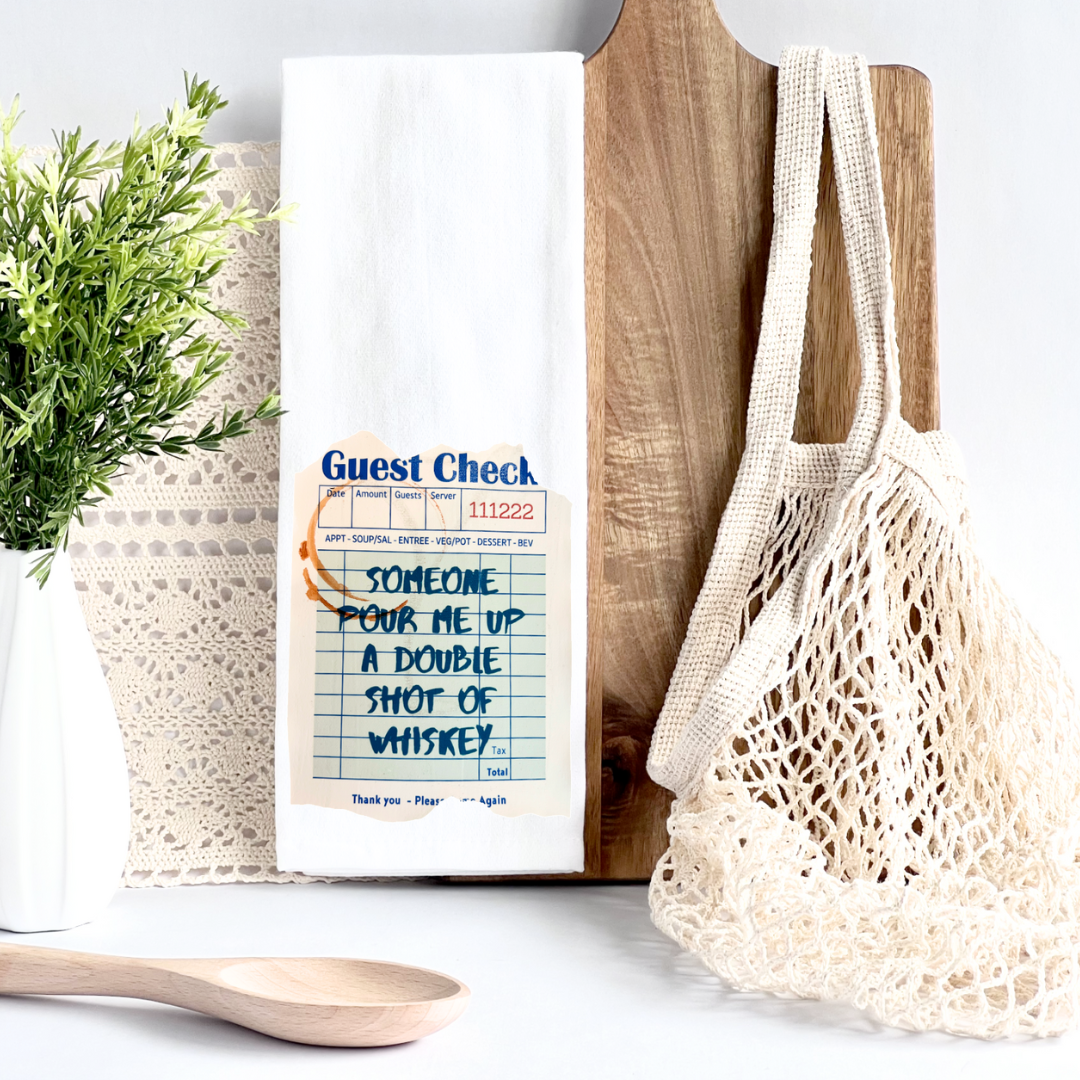 kitchen towel with a guest check design in blue, a shot glass ring and the words, someone pour me up a double shot of whiskey