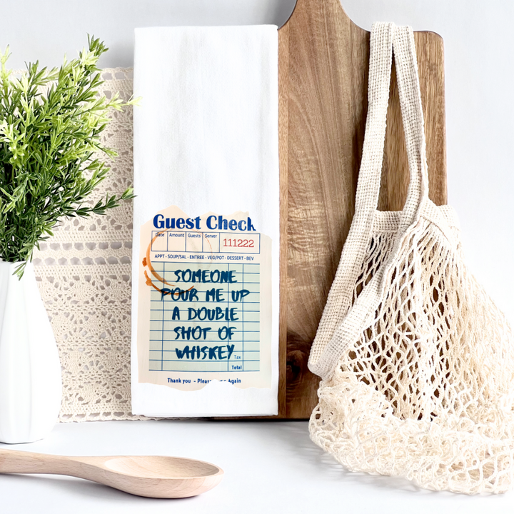 kitchen towel with a guest check design in blue, a shot glass ring and the words, someone pour me up a double shot of whiskey