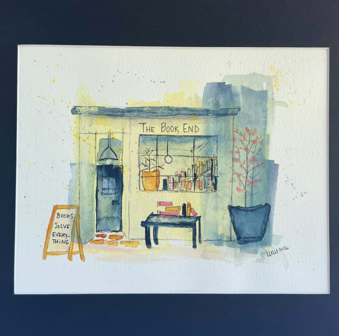 A watercolor painting of a mystery bookstore storefront labeled 'The Book End,' with a dark door, window display of books, a small table with books, potted plants, and a chalkboard sign reading 'Books Save Everything.' The artwork is painted on a white paper background with a dark navy border around it.
