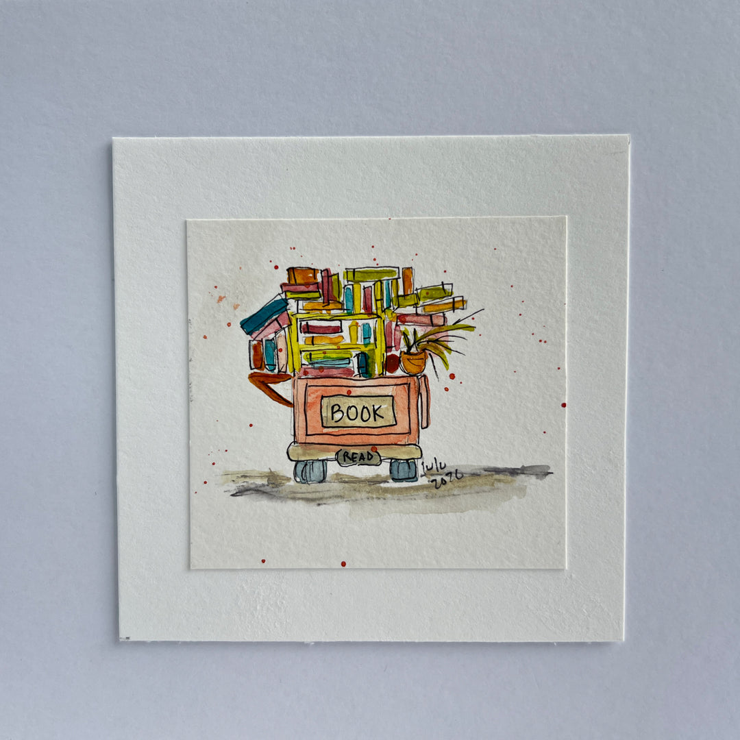 A square watercolor art print depicting a small book cart overfilled with colorful books and a potted plant, with the word “BOOK” written on the front.