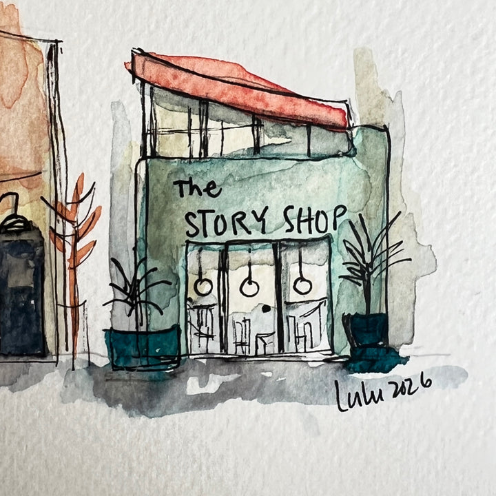 A horizontal watercolor art print depicting four whimsical bookstores with names including 'The Backlist', 'In the Margin, 'Paper & Ink', and 'The Story Shop'. The print is displayed on a textured light gray surface against a neutral gray background.