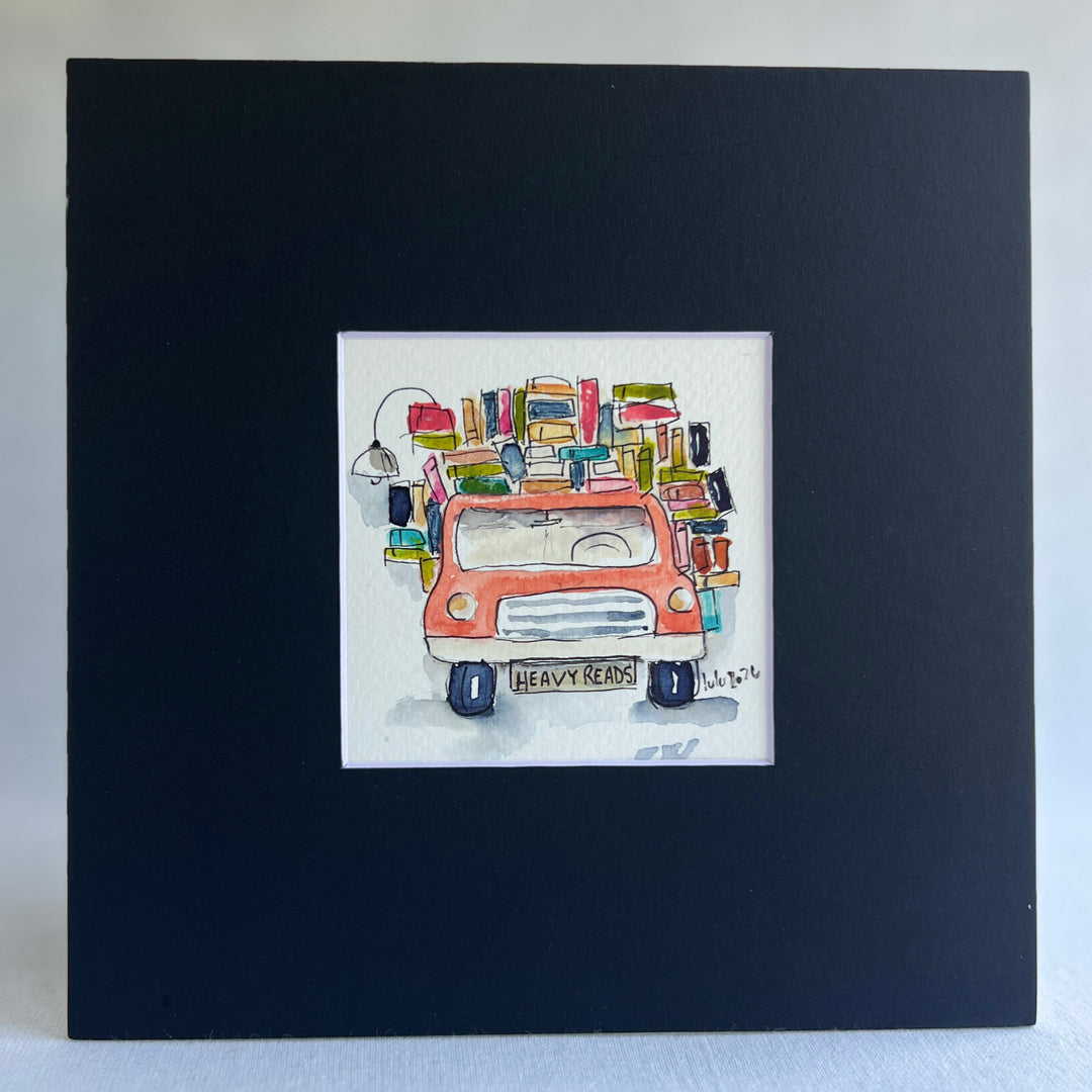 A square original watercolor art print depicting a red pickup truck loaded with colorful books and a wonky reading light, with the license plate reading 'HEAVY READS' 