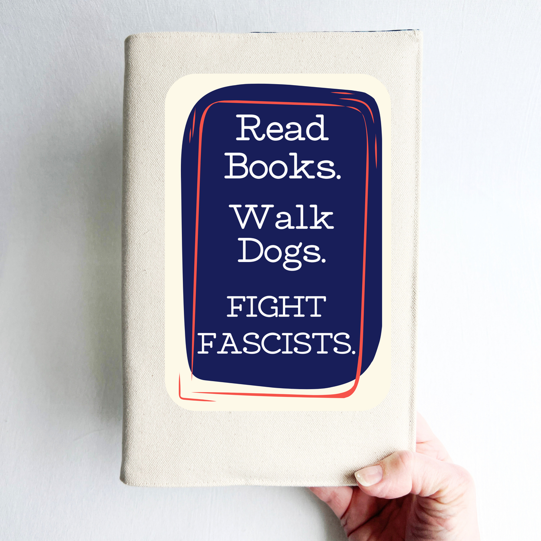 A canvas, reusable book cover in linen, with the words, 'Read Books. Walk Dogs. FIGHT FASCISTS.'  in white lettering placed on a rectangular navy box design.