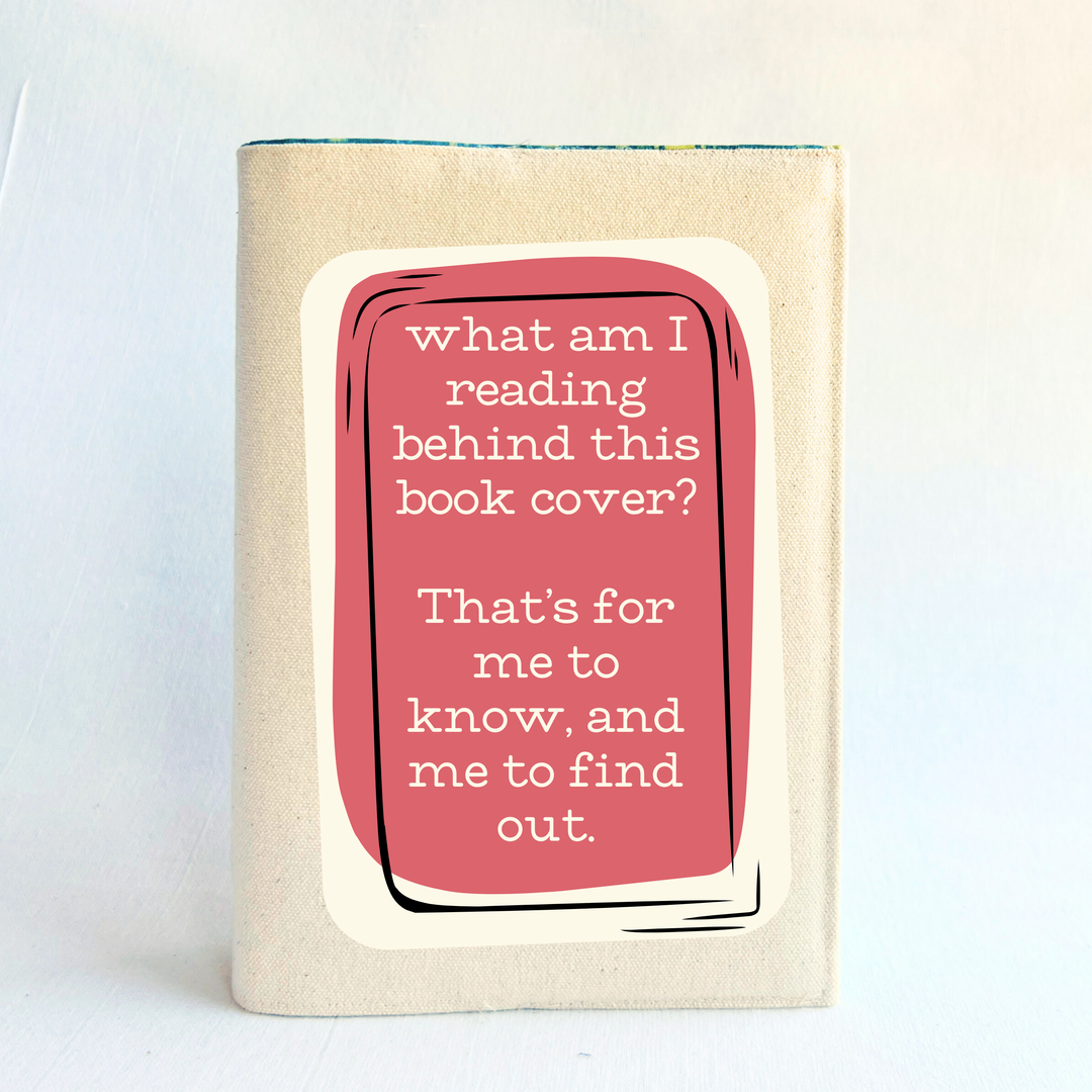 A canvas, reusable book cover in linen, with the words, 'what am I reading behind this book cover?  That's for me to know, and me to find out' in cream lettering, placed on a rectangular coral box design.