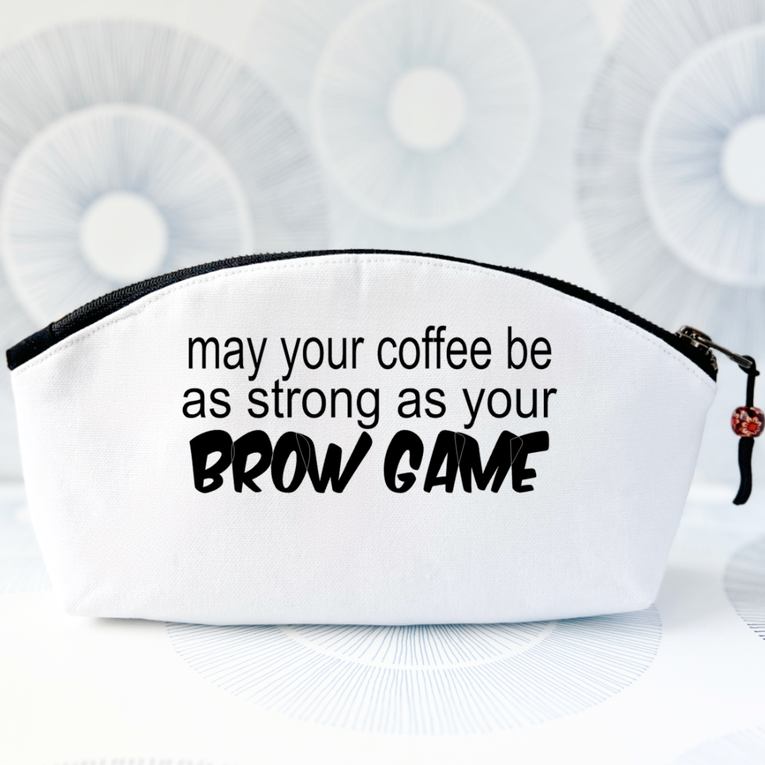 white canvas bag with a curvy top, a black zipper and the words, may your coffee be as strong as your brow game.