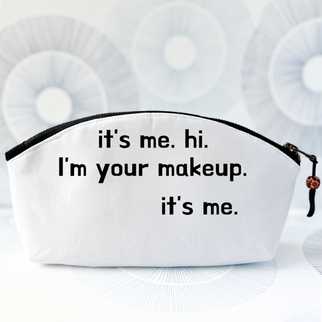 white canvas makeup bag with a curvy top, a black zipper and the words, it's me. hi. I'm your makeup. it's me.