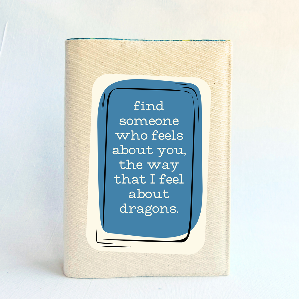 a book covered in linen-color reusable canvas adjustable book cover. A blue square is the background for the words, 'find someone who feels about you, the way that I feel about dragons.' in white lettering.