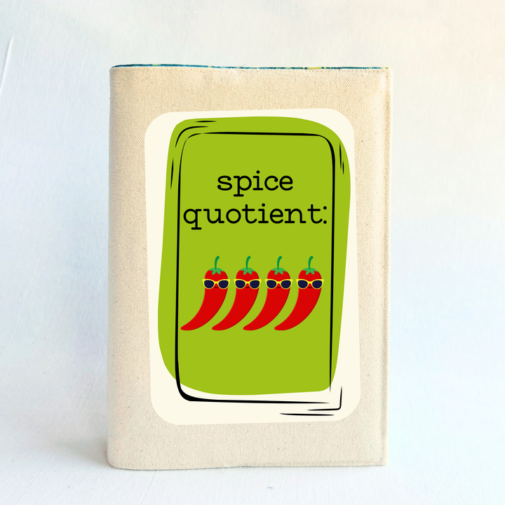 a book covered in linen-color reusable canvas adjustable book cover. A bright green square is the background for the words, 'spice quotient' in black lettering. Four cartoon peppers with sunglasses are layered on top.