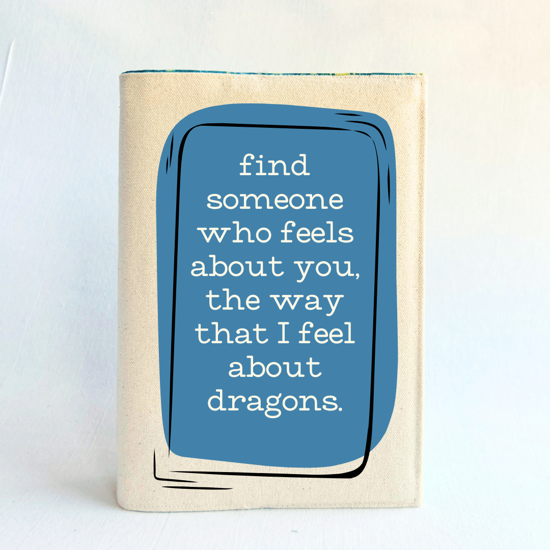 a book covered in linen-color reusable canvas adjustable book cover. A blue square is the background for the words, 'find someone who feels about you, the way that I feel about dragons.' in white lettering.