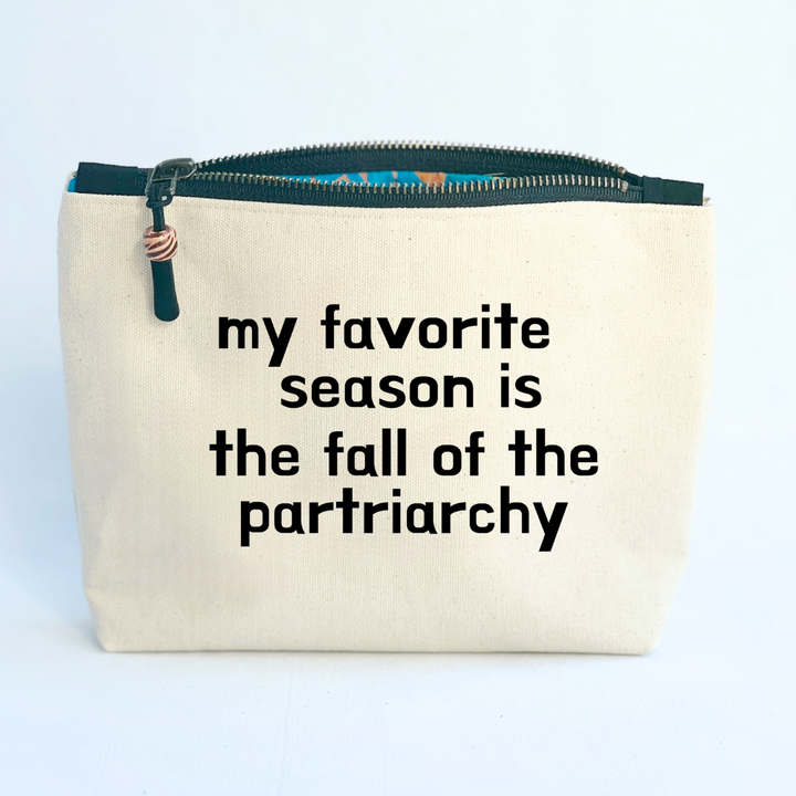 square linen-color canvas zip bag with black zipper and the words, my favorite season is the fall of the patriarchy.