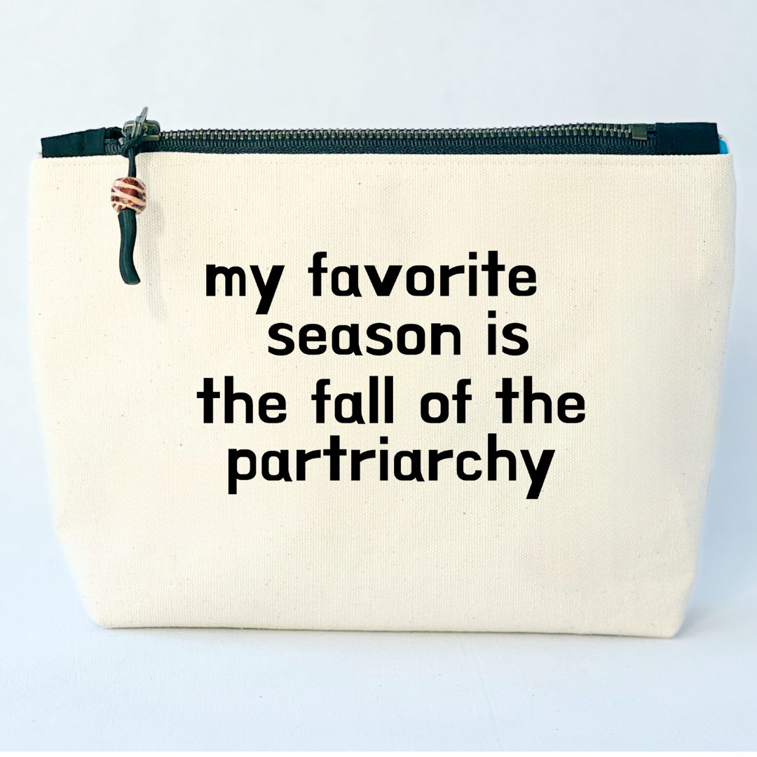 square linen-color canvas zip bag with black zipper and the words, my favorite season is the fall of the patriarchy.