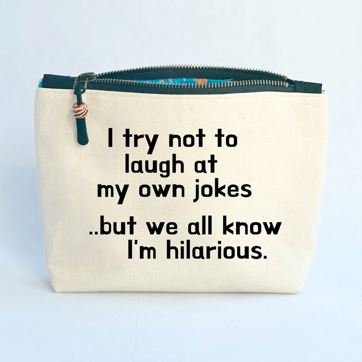 square linen-color canvas zip bag with a black zipper and the words, I try not to laugh at my own jokes..but we all know I'm hilarious
