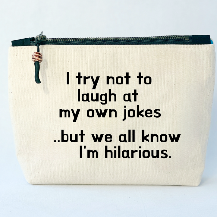 square linen-color canvas zip bag with a black zipper and the words, I try not to laugh at my own jokes..but we all know I'm hilarious