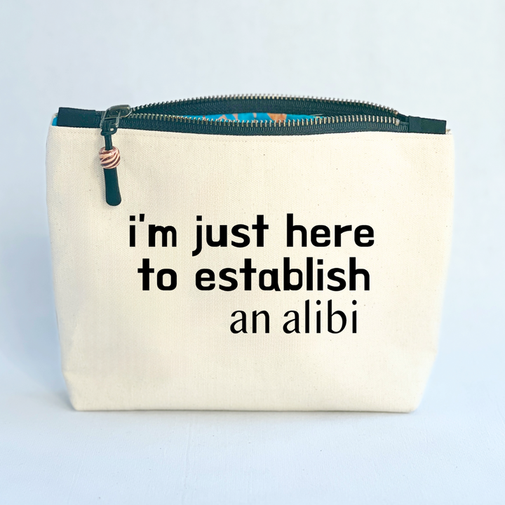 square canvas zip bag with black zipper and the words, i'm just here to establish an alibi
