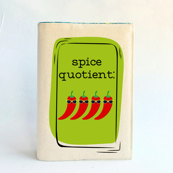 a book covered in linen-color reusable canvas adjustable book cover. A bright green square is the background for the words, 'spice quotient' in black lettering. Four cartoon peppers with sunglasses are layered on top.