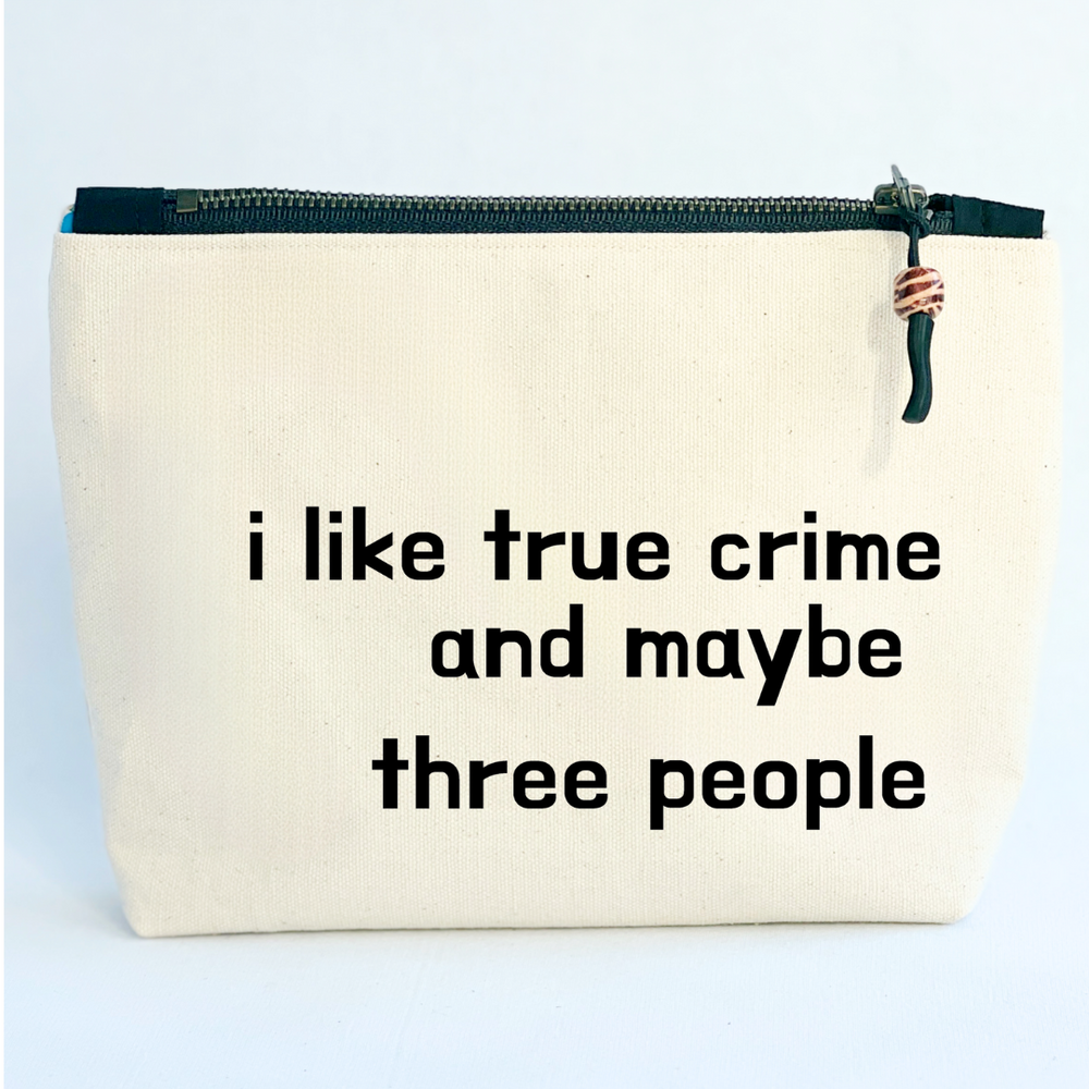 A linen-color square canvas zip bag with a black zipper and the words, I like true crime and maybe three people