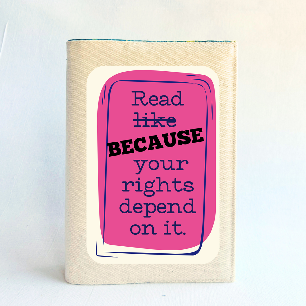 a book covered with a reusable book cover in linen, with the words, 'Read BECAUSE your rights depend on it', with navy lettering, placed on a deep pink box design.