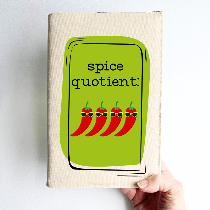 a hand holding a book covered in linen-color reusable canvas adjustable book cover. A bright green square is the background for the words, 'spice quotient' in black lettering. Four cartoon peppers with sunglasses are layered on top.