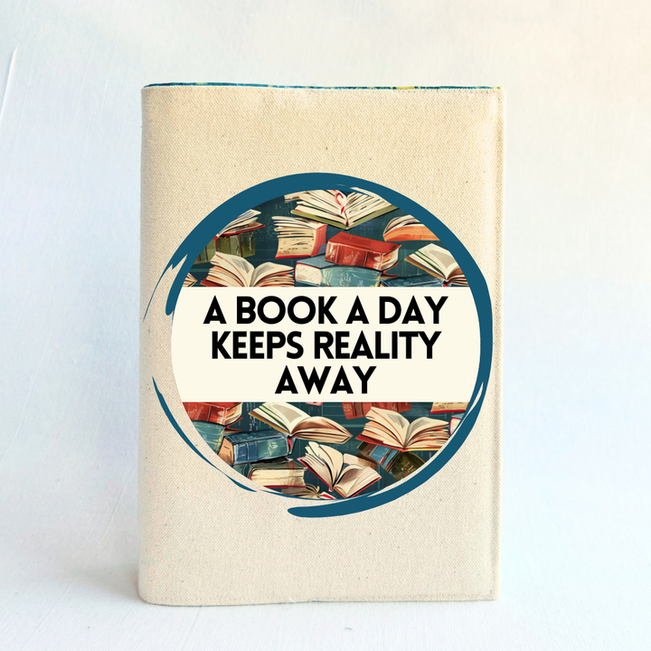 a book covered with a linen-colored canvas reusable book cover. A circular design with painted books is featured in the center of the cover, with the words, 'a book a day keeps reality away.'