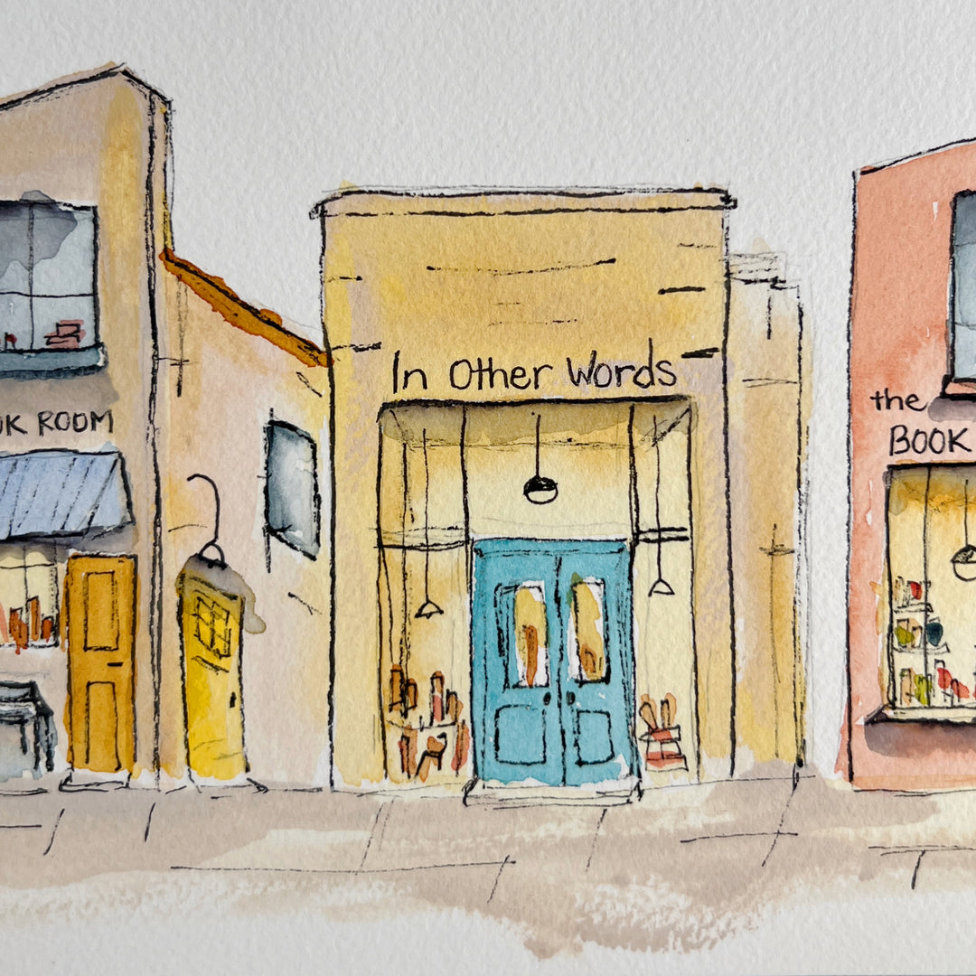 A watercolor art print depicting four stone bookstore buildings, presented with a wide white mat board against a neutral gray background.