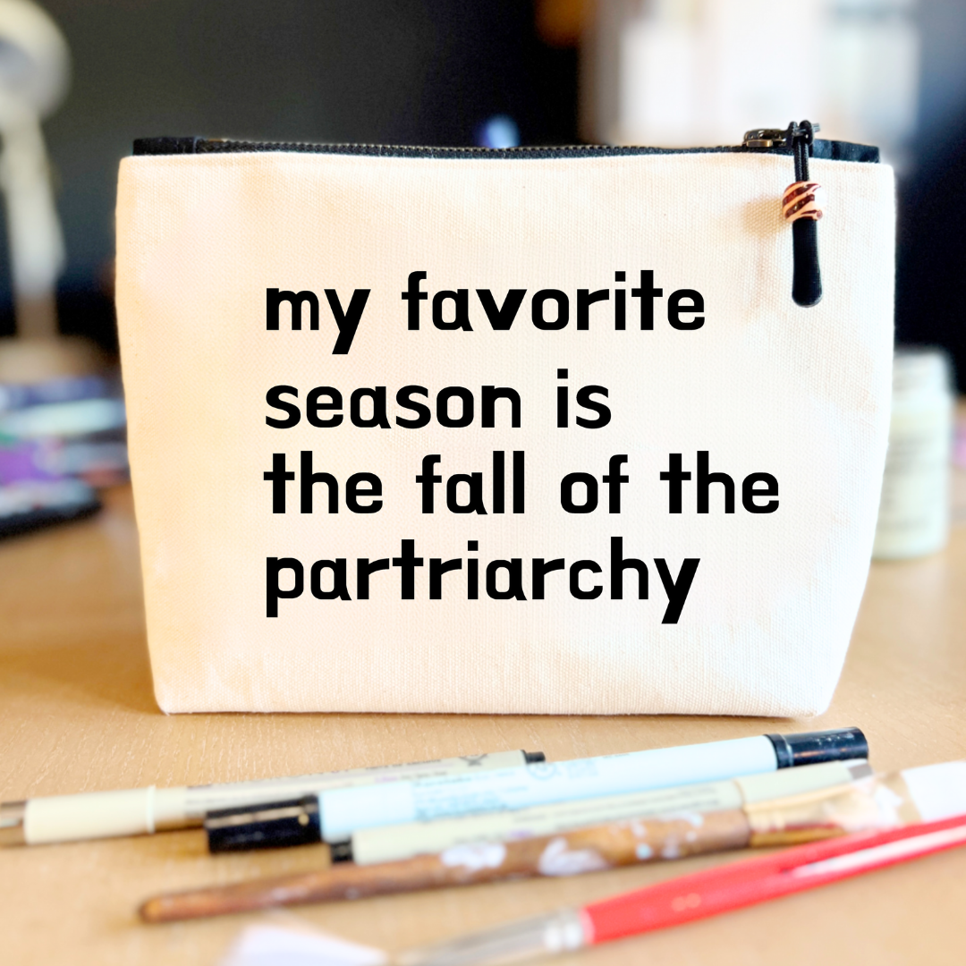 square linen-color canvas zip bag with black zipper and the words, my favorite season is the fall of the patriarchy.