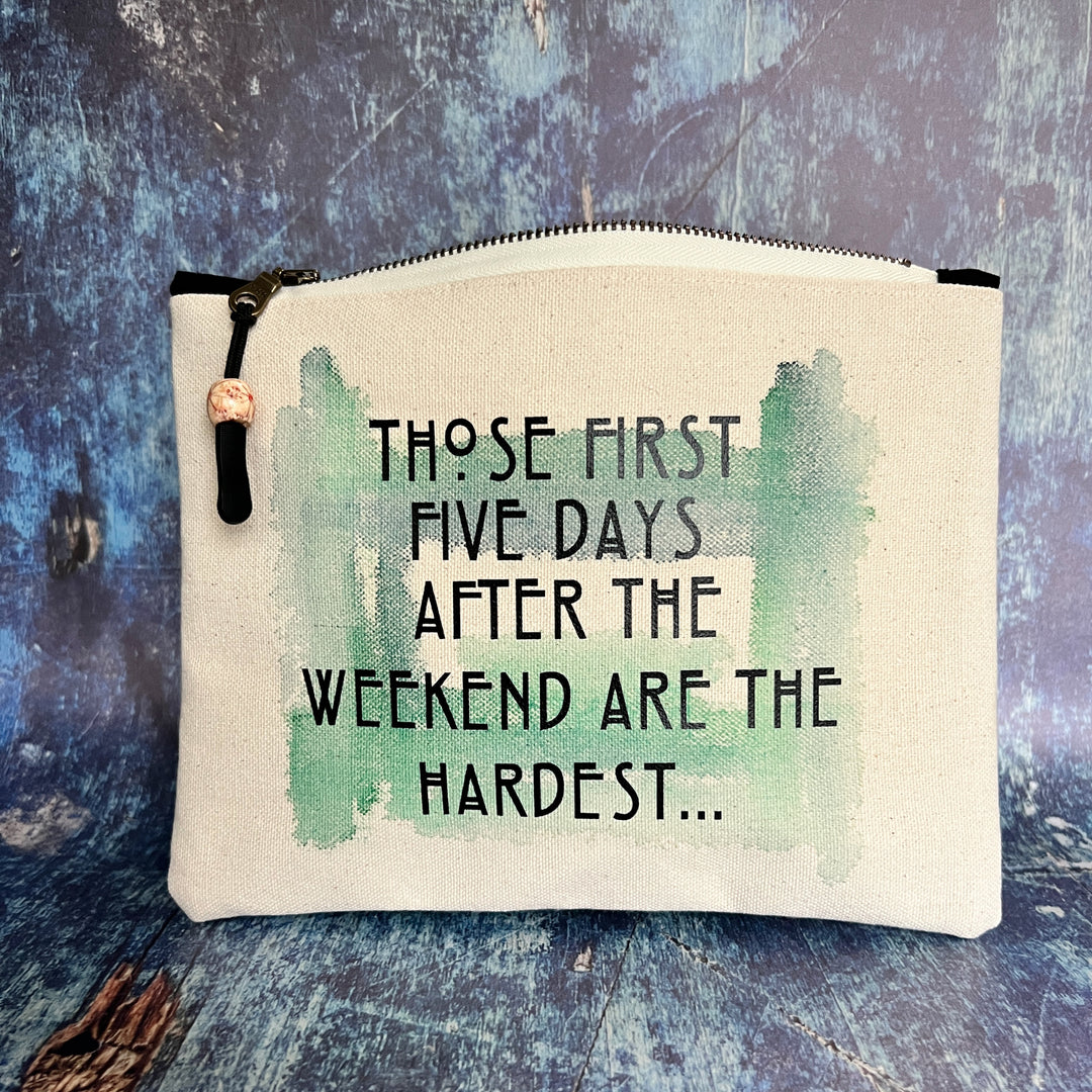 rectangular canvas zip pouch in linen color, with a zipper pull.  Green watercolor paint is the background for the words, those first five days after the weekend are the hardest, in black lettering.