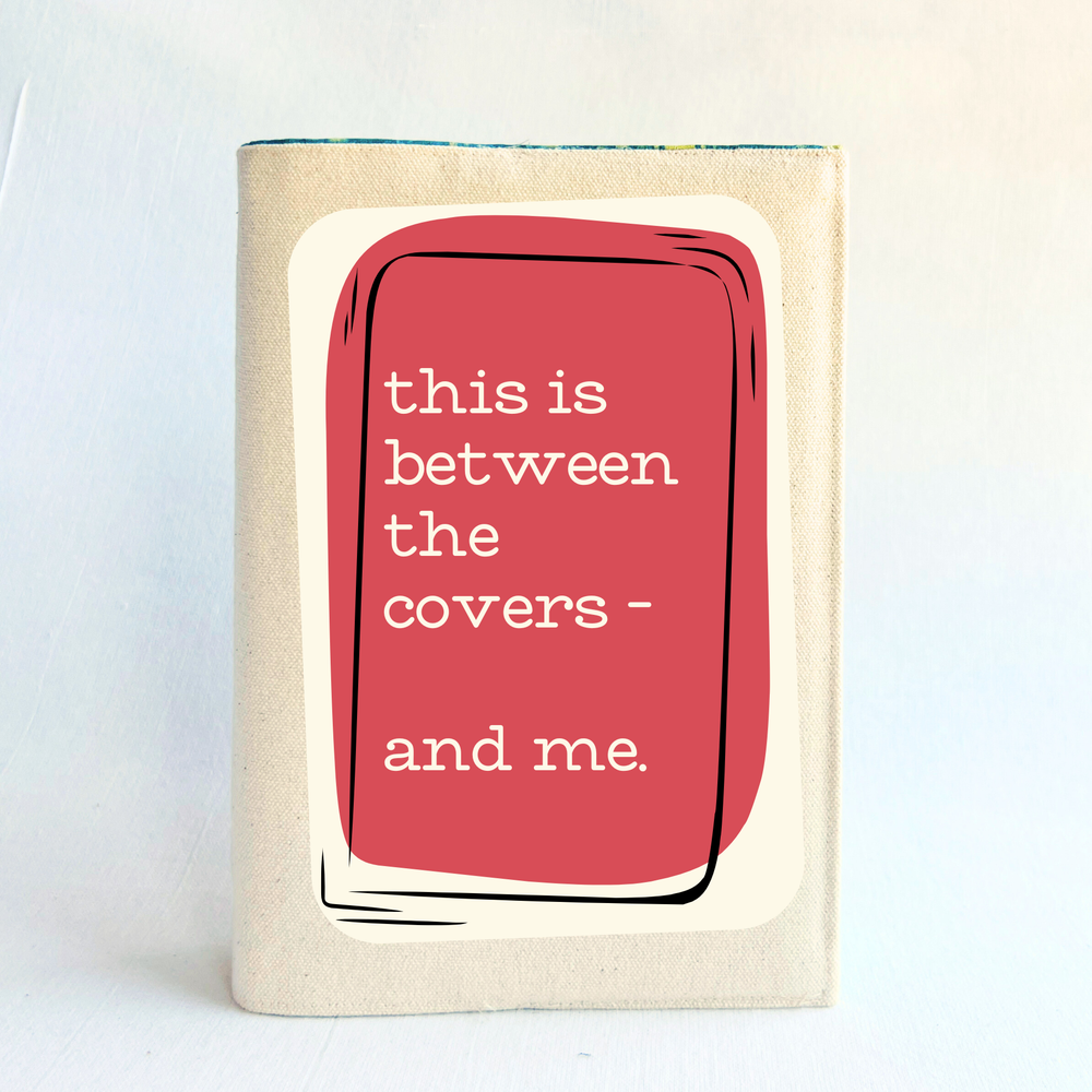 a linen-colored canvas book cover with a rose and cream graphic cover that reads 'this is between the covers - and me.' against a plain light background.