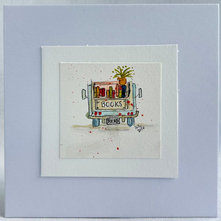 A square watercolor original art print featuring a hand-drawn and hand-painted illustration of a book cart with the word 'BOOKS' on the back and a small plant on top, displayed upright on stacked books.