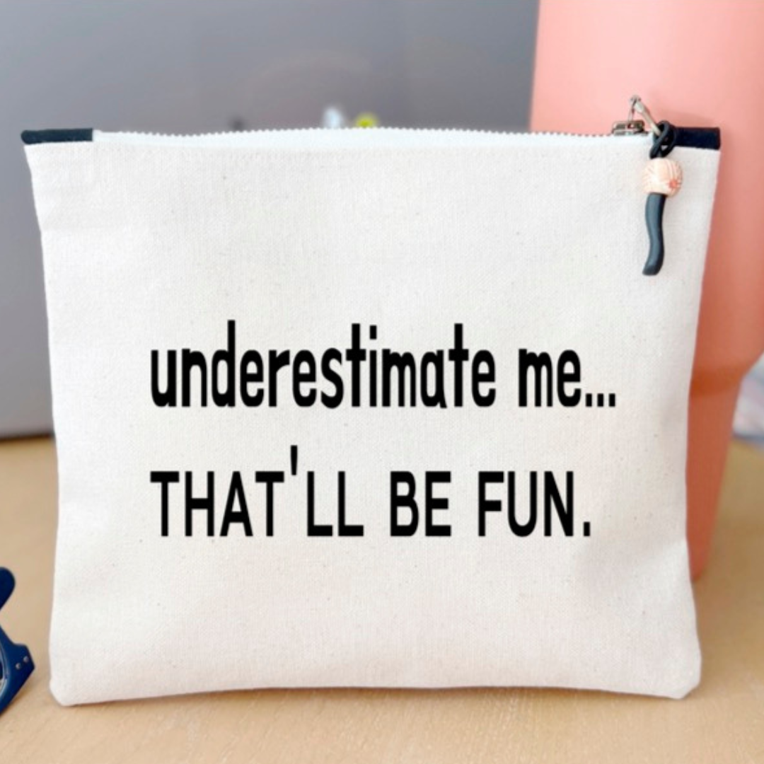 a canvas zip bag with the words, "underestimate me, that'll be fun" in black lettering