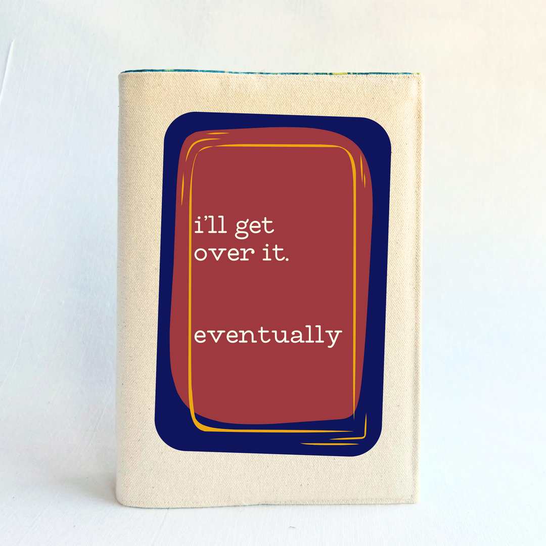 A linen-colored canvas book cover, featuring a graphic design of a red book with a navy blue and yellow border, containing the text 'i'll get over it. eventually' in white.