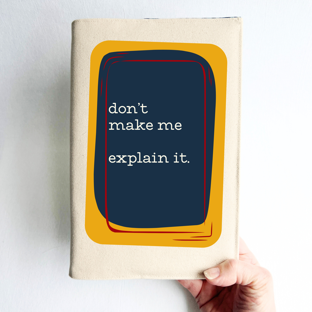 A linen-colored canvas book cover with a central graphic featuring a dark navy blue rectangle with white text that reads 'don't make me explain it.' The graphic is framed by a mustard yellow shape with thin red and orange accents
