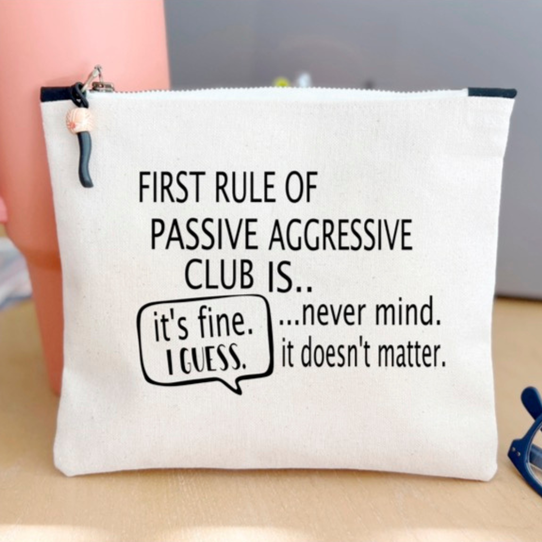 a canvas zip bag with  the words, "First rule of passive aggressive club is..never mind. it doesn't matter. it's fine. I guess."