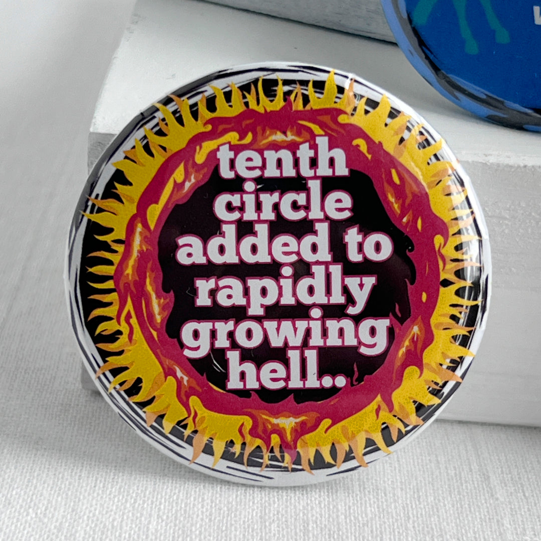 round pinback button with a black background, yellow and red flames surrounding the words, "tenth circle added to rapidly growing hell."