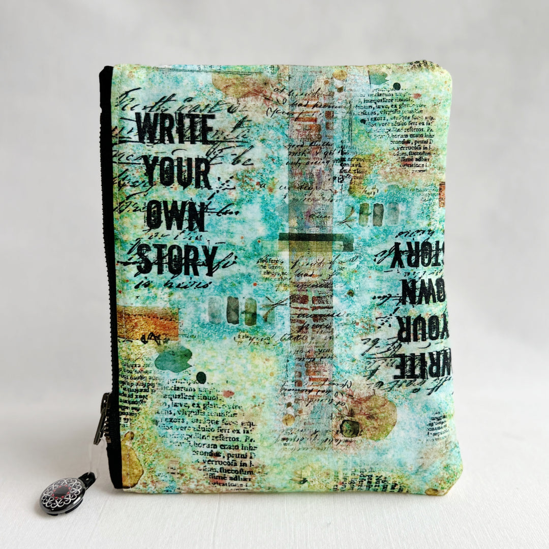 padded canvas zip bag with a mix of green and blue fabric and the words, Write Your Own Story, plus a colorful zipper pull and lining