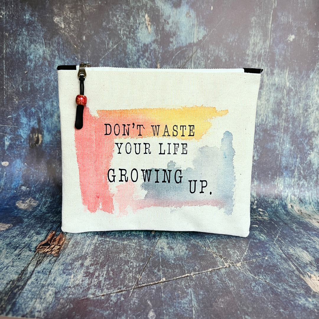 square canvas bag with paint swashes of pink, yellow and mayan blue, with the words, don't waste your life growing up.