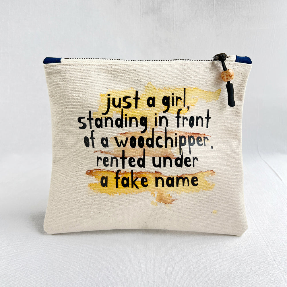 A canvas zippered pouch with a humorous quote printed on the front, featuring a yellow watercolor wash background and a black zipper with a decorative pull tab.