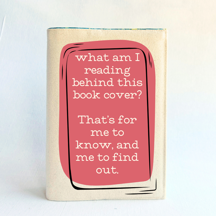A canvas, reusable book cover in linen, with the words, 'what am I reading behind this book cover?  That's for me to know, and me to find out' in cream lettering, placed on a rectangular coral box design.