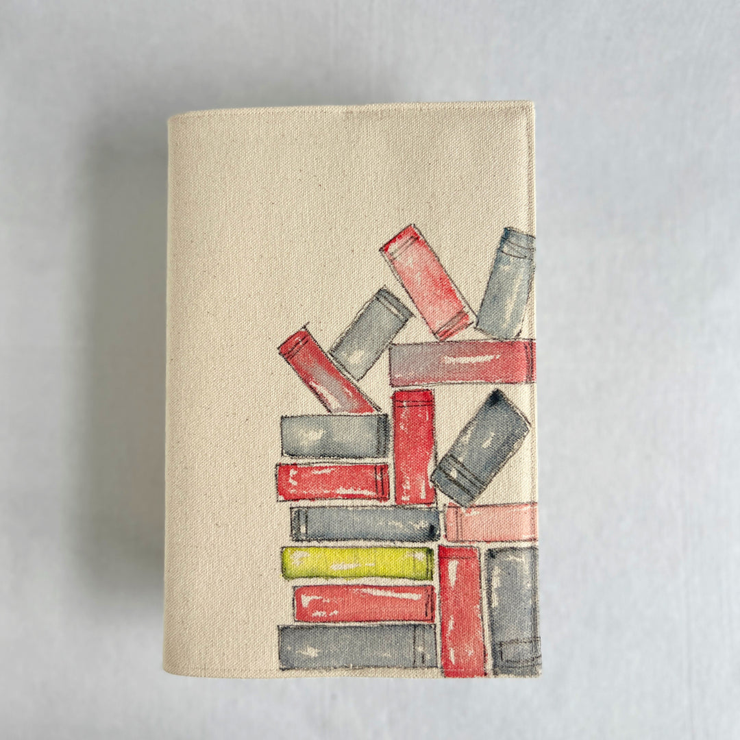 A rectangular canvas book cover featuring a watercolor illustration of stacked books in red, gray, and yellow on a beige background.