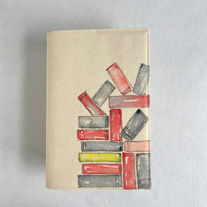 A rectangular canvas book cover featuring a watercolor illustration of stacked books in red, gray, and yellow on a beige background.