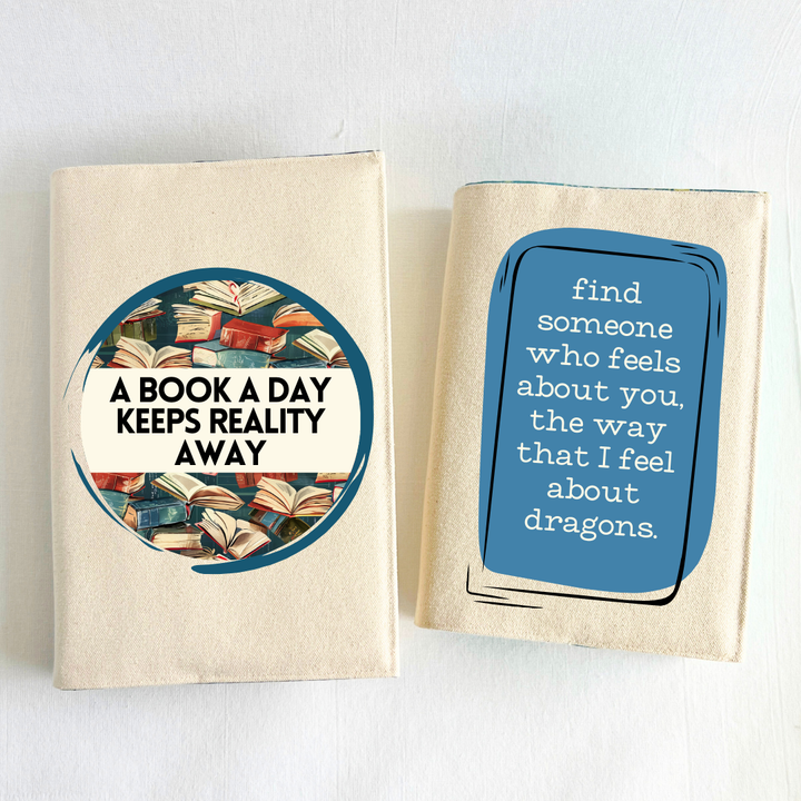a book covered with a linen-colored canvas reusable book cover. A circular design with painted books is featured in the center of the cover, with the words, 'a book a day keeps reality away.'  A second book with a canvas cover features a blue square design with the words, 'find someone who feels about you the way that I feel about dragons.'  Pictured as a display example of combining book covers  for gifting.