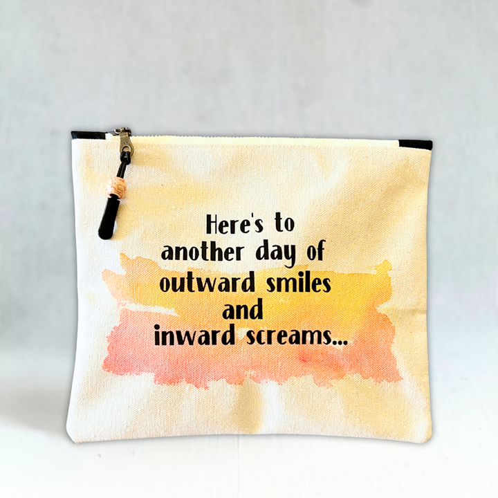 square canvas zip pouch with the words, Here's to another day of outward smiles and inward screams.'