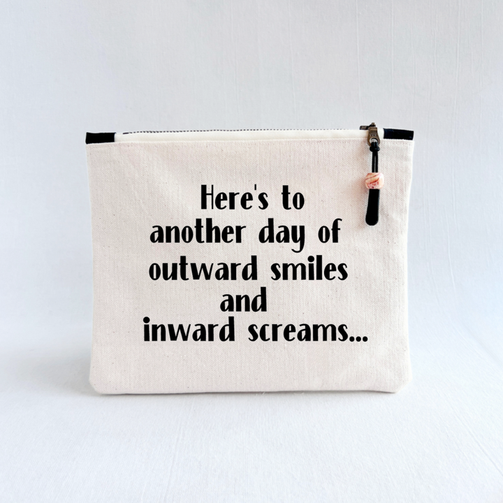 square canvas zip pouch with the words, Here's to another day of outward smiles and inward screams.'