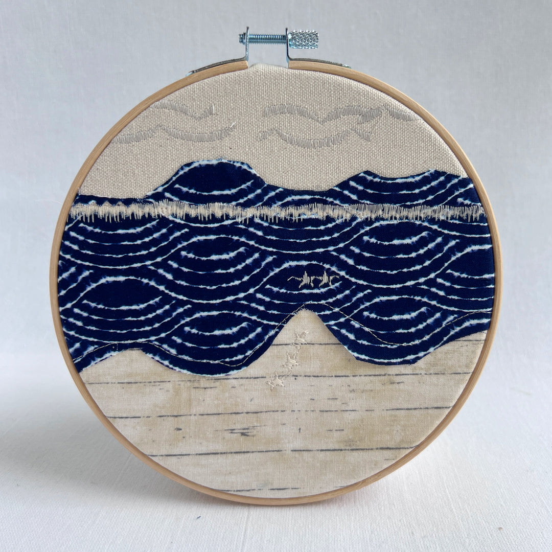 embroidery hoop art piece stitched fabric in shades of blue and yellow