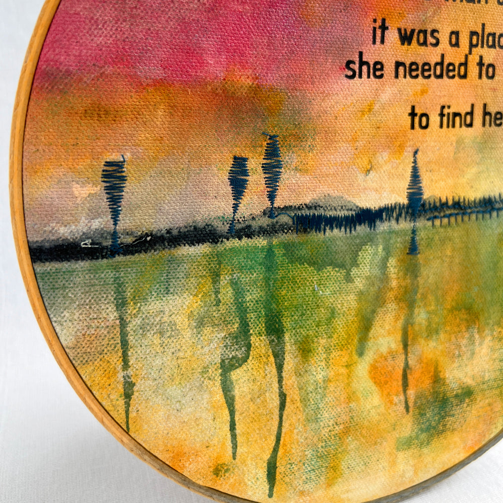 A large painted hoop art piece, with rose pinks, fresh greens and vibrant yellows, stitched with a rickety pier and finished with the words, for here, the ocean was more than a dream. it was a place she needed to visit to find herself.