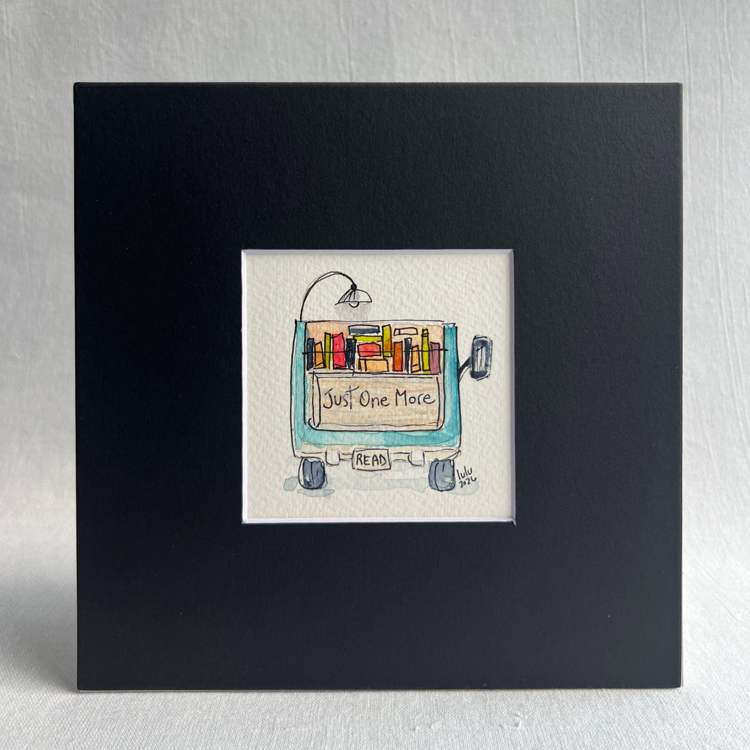A square original watercolor art print depicting the back end of a blue pickup truck loaded with colorful books and a wonky reading light, with the words, "Just One More' and a license plate with the word 'Read'