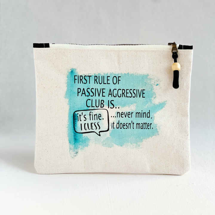 a canvas zip bag with blue watercolor painting and the words, "First rule of passive aggressive club is..never mind. it doesn't matter. it's fine. I guess."