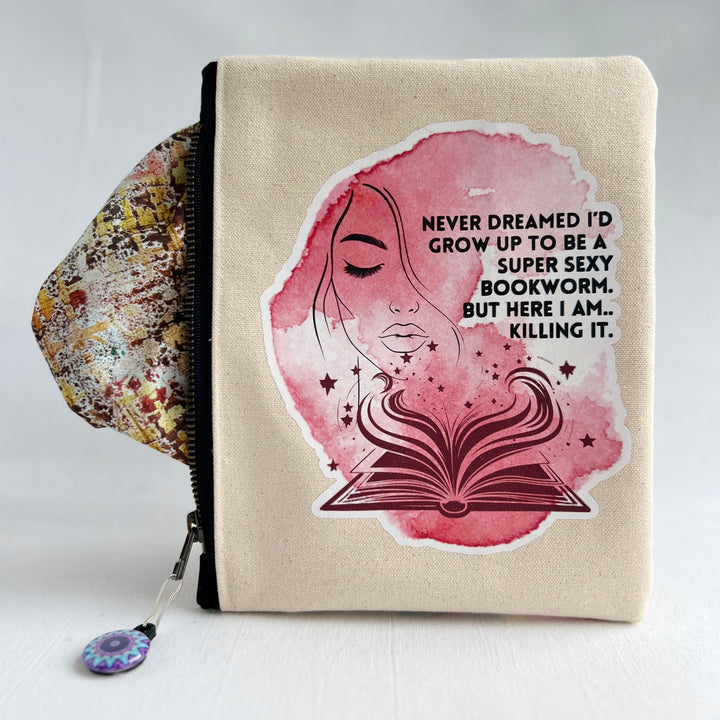 square oblong canvas zipper bag with a design of a face and an open book, with the words, "Never dreamed I'd grow up to be a super sexy bookworm. But here I am..killing it."