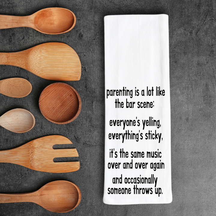 rectangular white kitchen towel with the words, parenting is lot like the bar scene: everyone's yelling, everything's sticky, it's the same music over and over again and occasionally someone throws up.